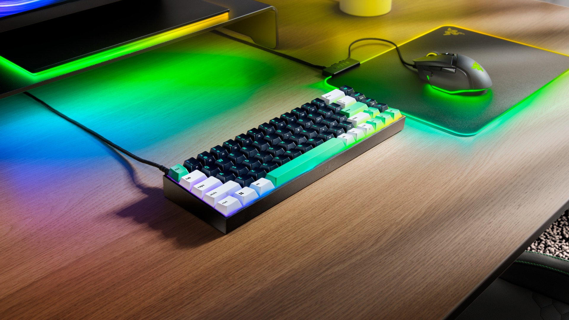 Razer Reclusa X Mini 65% sobre a mesa ao lado de um mouse Razer, com iluminação RGB